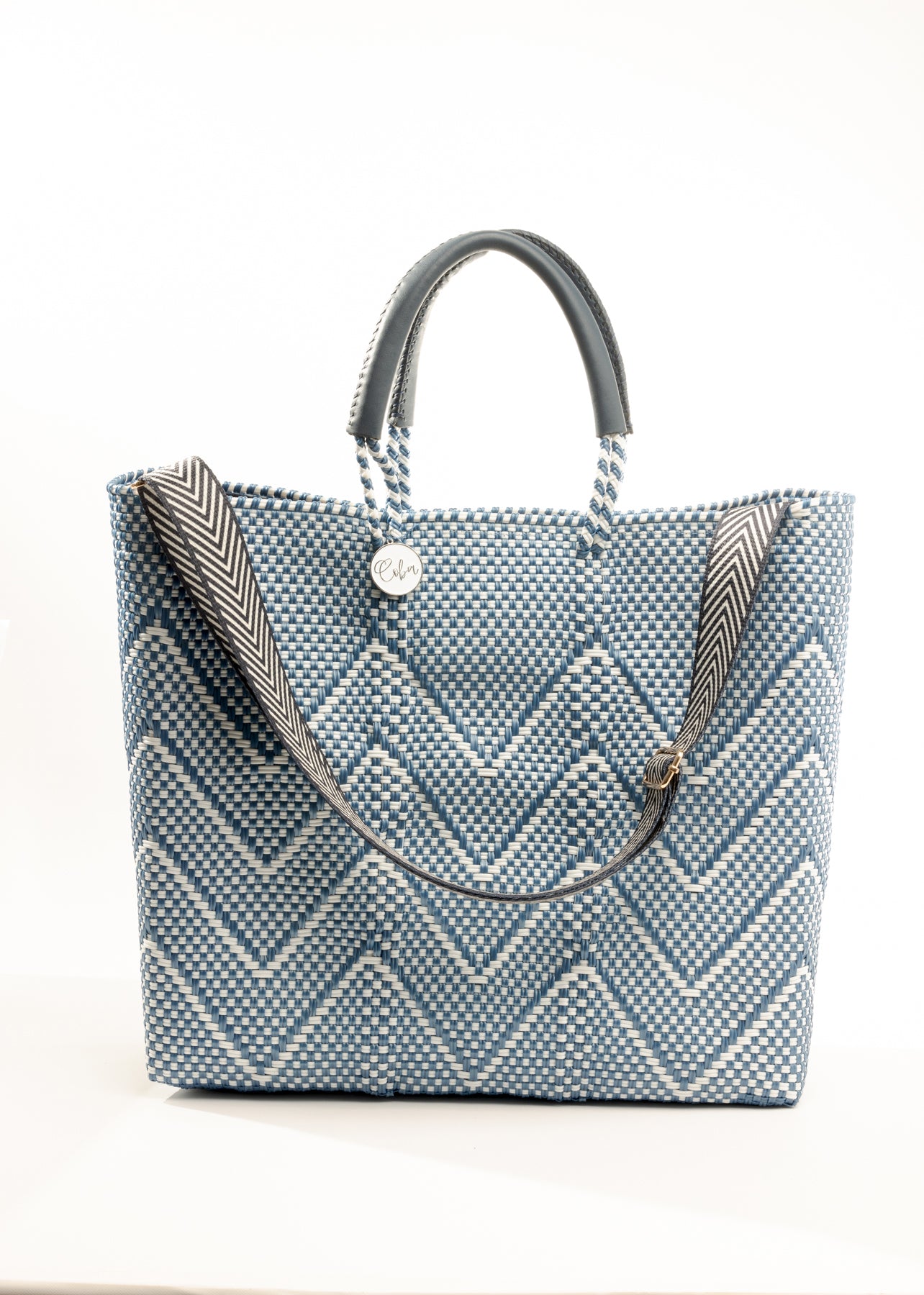 Herringbone pattern purse strap clipped to blue and white chevron tote bag