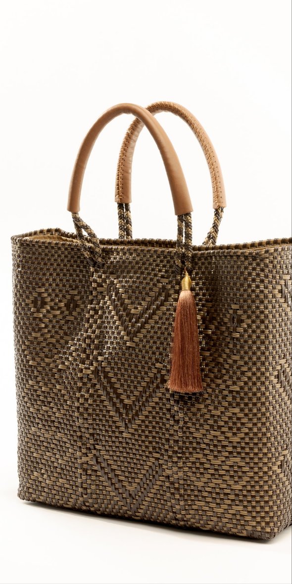 Side angle of brown and tan chevron woven bucket bag made from recycled plastics and featuring a tan leather handle and tassel detail